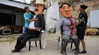 Dos jóvenes preparan monigotes, conocidos como ‘Año Viejo’, que representan a la presidenta de Honduras, Xiomara Castro, y al expresidente Honduras, Manuel Zelaya, este domingo en la aldea de Germania, al sur de Tegucigalpa (Honduras).