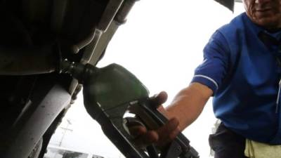 Un empleado llena el tanque de combustible de un auto.