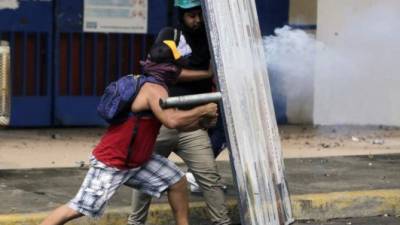 Un manifestante dispara un mortero casero desde atrás de un escudo improvisado durante los enfrentamientos con la policía antidisturbios en una manifestación realizada por estudiantes universitarios de ingeniería en Managua el 28 de mayo de 2018.AFP