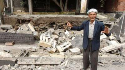 Un anciano señala los escombros tras el fuerte sismo.