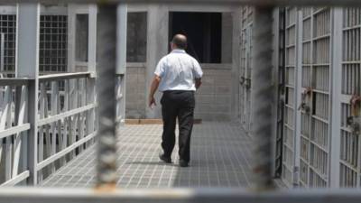 Hombre camina fuera de las celdas de una cárcel en Honduras.