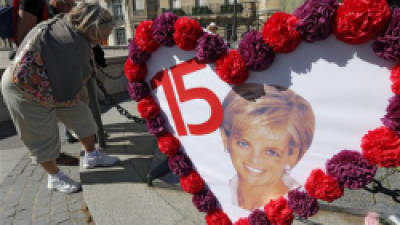 Tourists stand in front of the Flame of Liberty monument to Diana, where flowers, photos and messages are placed around, in Paris, Friday Aug. 31 2012. Admirers from around the world are paying tribute to Princess Diana at the Paris tunnel where she was killed in a car crash 15 years ago. (AP Photo/Jacques Brinon)