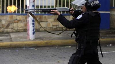 TOPSHOT - A riot police officer fires a weapon during clashes with students taking part in a protest in Managua on May 28, 2018. / AFP PHOTO / INTI OCON