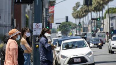 Personas se protegen con una mascarilla para evitar el contagio de COVID-19 en EEUU. Foto: AFP