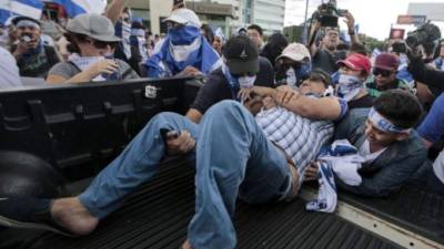 An protester who was shot in the arm, is loaded into a pick-up van by fellow demonstrators, during a march against Nicaraguan President Daniel Ortega's government in Managua, on September 2, 2018. At least two people were injured on Sunday, when alleged paramilitaries fired against an opposition march, which ended up in violence in eastern Managua. / AFP PHOTO / INTI OCON