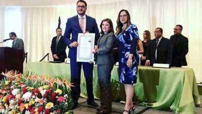 Representantes de la Comisión para la Defensa y Promoción de la Competencia al momento de recibir el pergamino. Foto Periódico Digital.