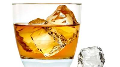 Whiskey with ice cubes in rocks glass on white background