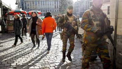 Varios soldados hacen hoy guardia en las calles, mientras los transeúntes pasean tranquilamente pese a continuar en máxima alerta terrorista desde el 22 de noviembre en Bruselas, Bélgica. EFE