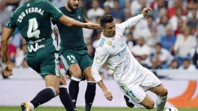 GRA672. MADRID, 20/09/2017.- El delantero portugués del Real Madrid, Cristiano Ronaldo (d), cae ante los defensores del Real Betis, el marroquí Zouhair Feddal y Antonio Barragán, durante el encuentro correspondiente a la quinta jornada de primera división que disputan esta noche en el estadio Santiago Bernabéu, en Madrid. EFE / Javier López.