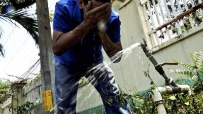 Un sampedrano mitiga el calor mojándose la cara en una calle de la ciudad. Fotos:José Cantarero.