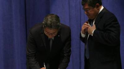 El presidente Juan Orlando Hernández firma junto al secretario Leonel Ayala.
