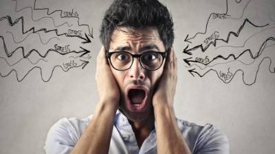 Young man wearing glasses holding his head screaming