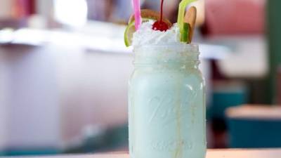 Decore la malteada con galletas María partidas por la mitad y una cereza.