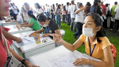 Job recruiters wear surgical masks as precaution against A(H1N1) virus commonly known as swine flu as they interview applicants at a three-day Government-sponsored jobs fair Friday June 12, 2009 at Manila's Rizal Park in the Philippines. The World Health Organization declares a Swine Flu pandemic on Friday, the first in 41 years. (AP Photo/Bullit Marquez)