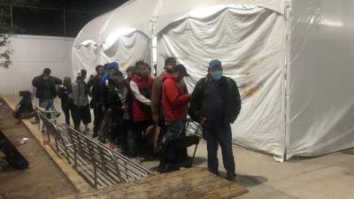 Un grupo de migrantes esperan para entrar a un albergue en Ciudad Juárez.