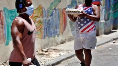 Un hombre con tapabocas carga este lunes dos paquetes de huevos, en La Habana (Cuba). EFE/Ernesto Mastrascusa