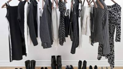 Female black and white clothes on a pole and shoes on a wooden floor.