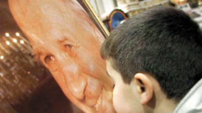 A child kisses a photo of Pope John Paul II after a Mass for the repose of the Pope, celebrated in the church of Santa Maria alla Carita' in Naples, Italy, Sunday, April 3, 2005. The Vatican announced that John Paul died at 21:37 local time Saturday, April 2, after a long struggle against debilitating illness. He was 84. (AP Photo/Salvatore Laporta)