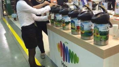 Dos asistentes coreanas prueban una de las muestras de café en el stand de exhibición de Honduras.