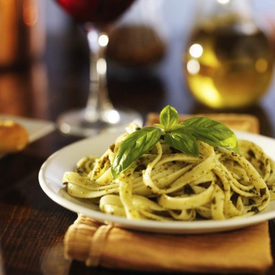 italian fettuccine in basil pesto sauce on dinner table at night