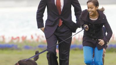 President Barack Obama watches as Malia shows off their new dog Bo, a 6-month-old Portuguese water dog, on the South Lawn of the White House in Washington, on Tuesday, April 14, 2009. (AP Photo/Ron Edmonds)