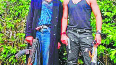 Dos de los supuestos delincuentes portan fusiles AK-47 en medio de un cafetal.