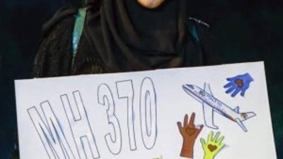 Una mujer sostiene una pancarta que reza 'MH370. Nosotros recordamos' durante una ceremonia en recuerdo de las víctimas del vuelo MH370.