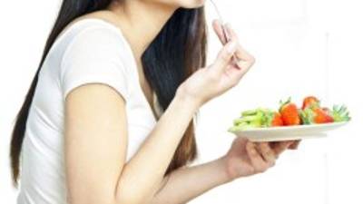 Young woman enjoying fruit salad on a contemporary kitchen.
