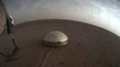 Las nubes se desplazan sobre el sismómetro cubierto en la cúpula, conocido como SEIS, perteneciente al módulo de aterrizaje InSight de la NASA, en Marte.
