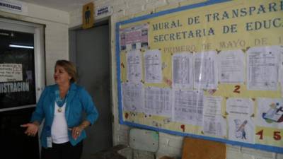 La secretaria departamental Gloria Alvarenga observando el mural de transparencia del colegio.