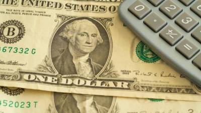 Dollar banknotes and a calculator are lying on a table