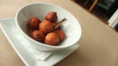 Disfrute de unos crujientes buñuelos de yuca en miel.