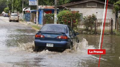 Vehículo turismo avanza por una calle inundada por las lluvias | Fotografía de archivo