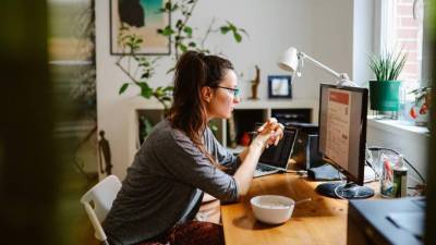 Una mujer sentada frente a la computadora haciendo teletrabajo.