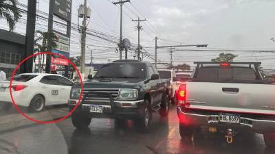 Vehículo turismo con registro de taxi avanza por la acera de una calle que conecta con el bulevar del Este.