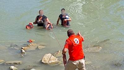 Un agente mexicano lanza una cuerda para rescatar a tres migrantes que estaban a punto de ahogarse en el río Bravo.