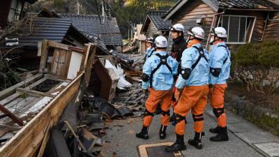 Miembros de un equipo de rescate observan los escombros de unas casas tras el terremoto en Japón.