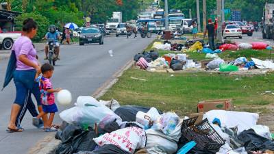Personas transitan por la 33 calle, donde pobladores de colonias aledañas han sacado su basura a la mediana.