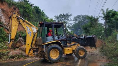 Hombre con excavadora despeja la carretera que conduce de Omoa a Guatemala luego del derrumbe provocado por las lluvias.