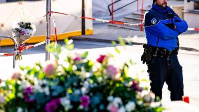Un policía monta guardia junto a flores depositadas cerca del lugar del incendio declarado en el bar-lounge Le Constellation, este jueves en Crans-Montana, Suiza.