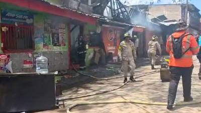 Negocio consumido por las llamas, mientras el Cuerpo de Bomberos realiza labores de emergencia para sofocar el incendio.