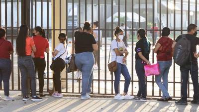 Un grupo de personas buscan empleo en San Pedro Sula con su hoja de vida en mano.