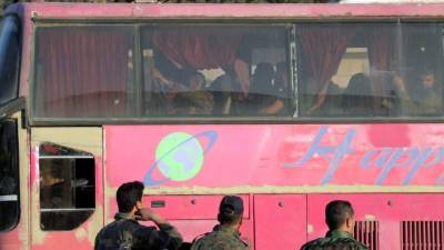 Autobuses del gobierno, con decenas de combatientes del Ejército al-Islam a bordo, salen de la ciudad de Douma. EFE