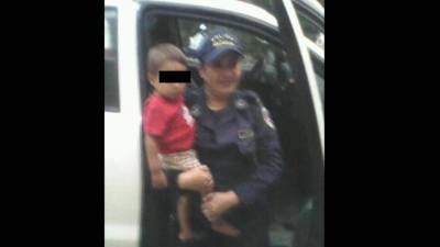 Una policía carga al menor en sus brazos tras encontrarlo desprotegido.