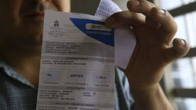 Un hombre muestra una factura de energía eléctrica.