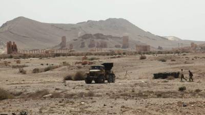 Militares sirios caminan frente a las murallas de la antigua ciudad de Palmira.