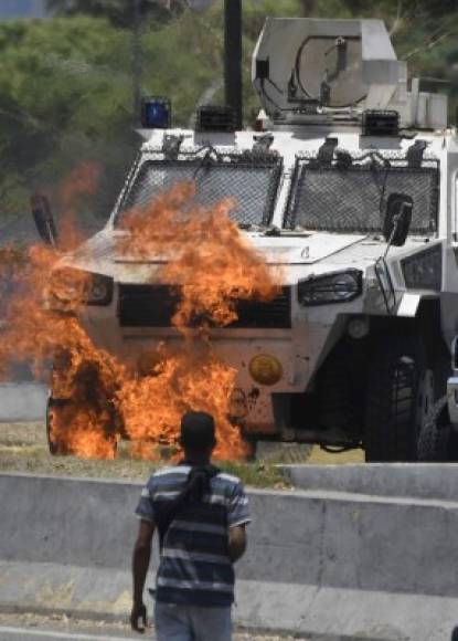 An opposition demonstrator looks at an armoured vehicle in flames during clashes with soldiers loyal to Venezuelan President Nicolas Maduro after troops joined opposition leader Juan Guaido in his campaign to oust Maduro's government, in the surroundings of La Carlota military base in Caracas on April 30, 2019. - Guaido -- accused by the government of attempting a coup Tuesday -- said there was 'no turning back' in his attempt to oust President Nicolas Maduro from power. (Photo by Federico PARRA / AFP)