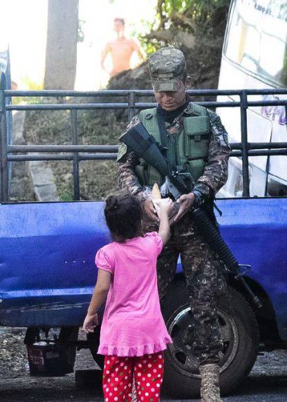 Esta es la imagen del día. Una niña dándole comida a un militar salvadoreño.