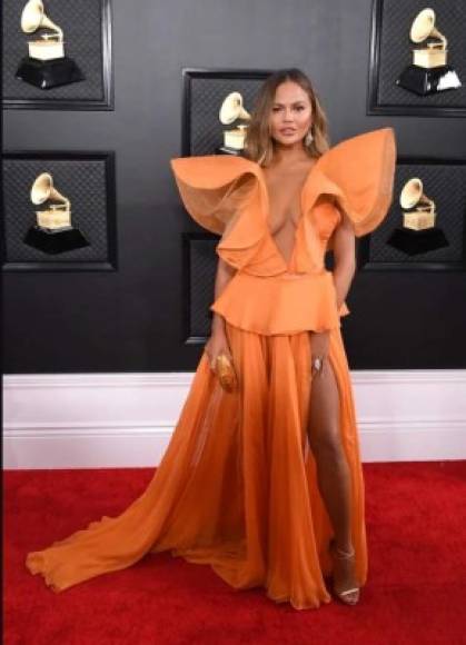 Chrissy Teigen destacó en la alfombra con su vestido naranja de Yanina Couture.