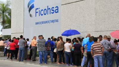 Decenas de sampedranos hacen fila en las afueras de una sucursal de Banco Ficohsa. Foto: Cristina Santos